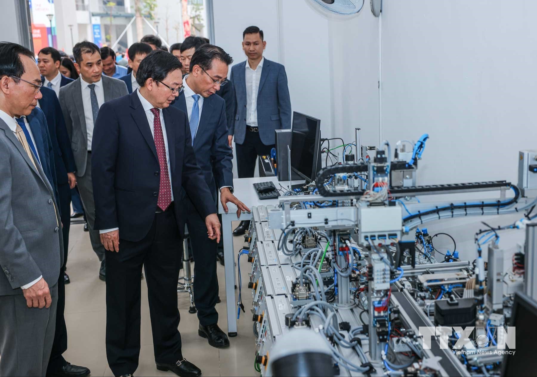 Phó Thủ tướng Hồ Quốc Dũng và các đại biểu tham quan máy móc tại Trung tâm Thực hành tập trung của Trường Đại học Công nghệ. (Ảnh: Hoàng Hiếu/TTXVN)